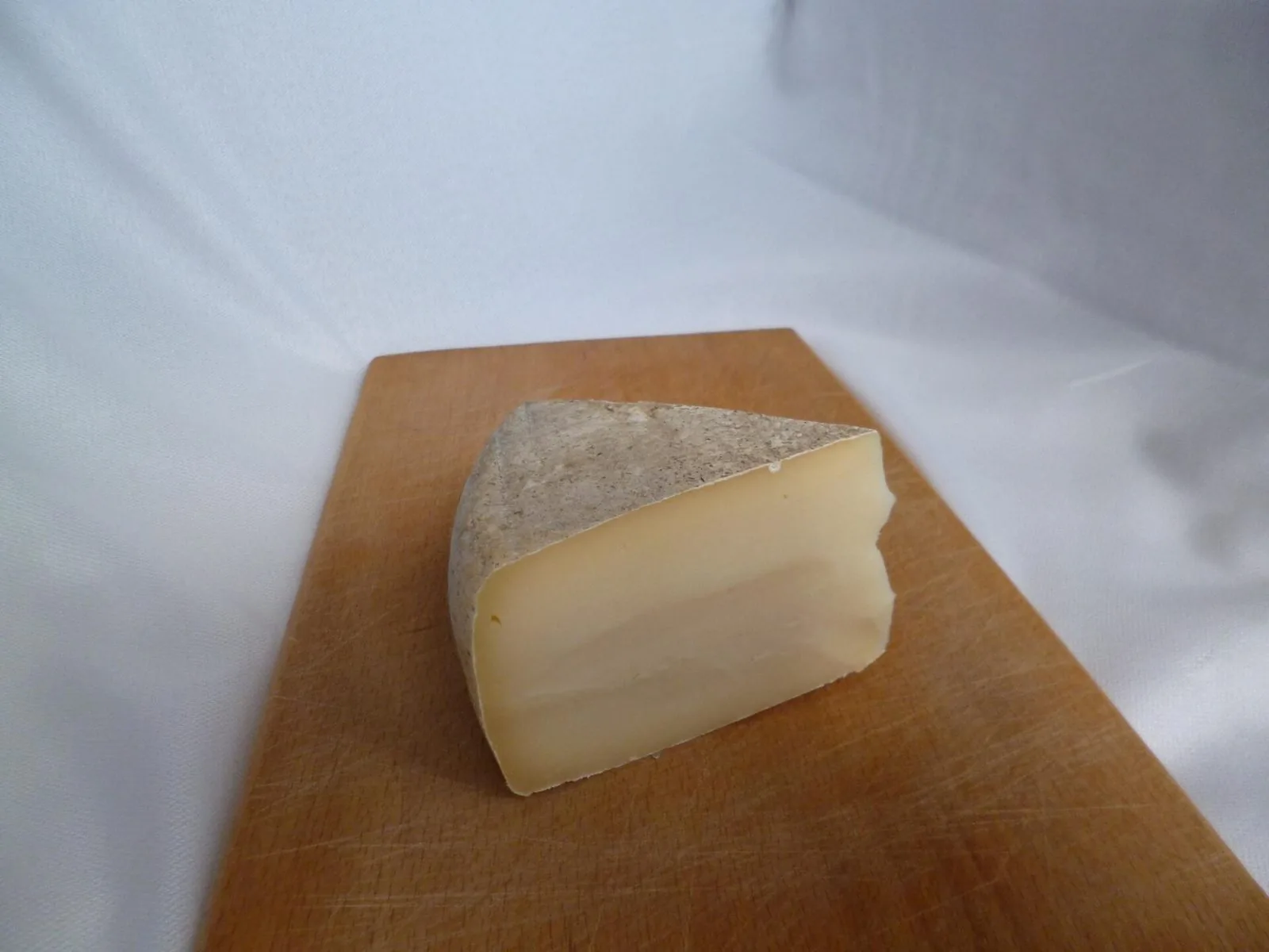 Spicchio di toma, formaggio tipico piemontese, su un tagliere di legno