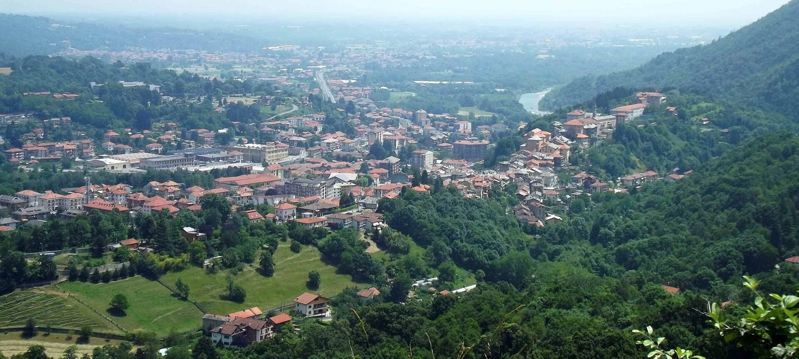 Panorama di Lanzo Torinese tra colline boscose, con la valle della Stura che si apre verso la pianura