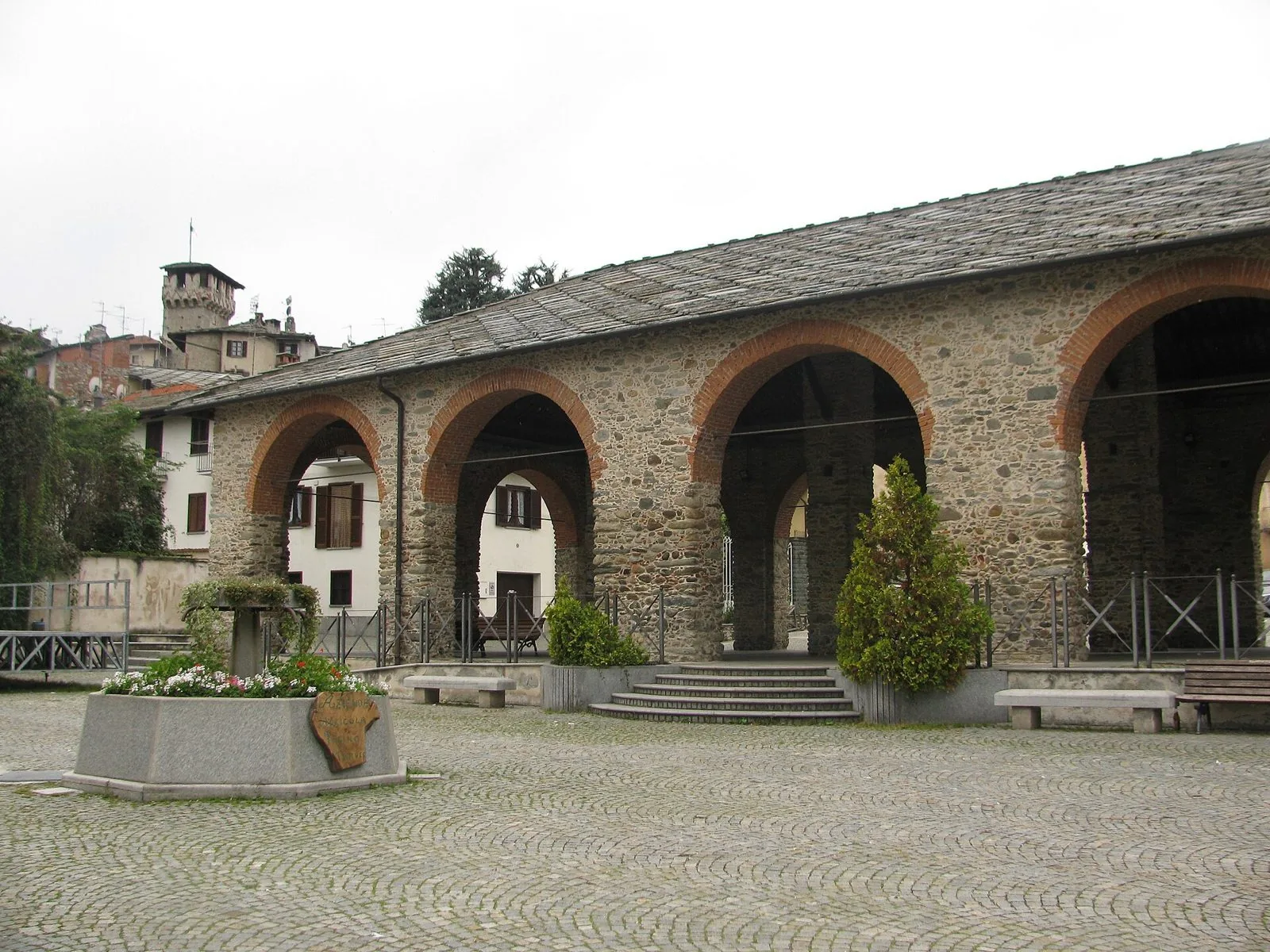 L'antica ala mercatale in pietra di Piazza Allisio a Lanzo Torinese con la torre sullo sfondo